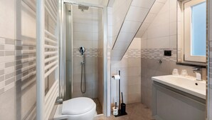 Un baño moderno con ducha de vidrio, inodoro, lavamanos y espejo.