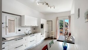 Una cocina moderna con armarios blancos, una mesa de comedor con sillas y vistas al exterior a través de un ventanal amplio.