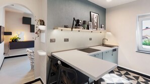 A modern kitchen with a white countertop, black chairs, and a window with a view. - ‘Torri e Tramonti’ Apartment with Private Terrace and Air Conditioning (Albenga)