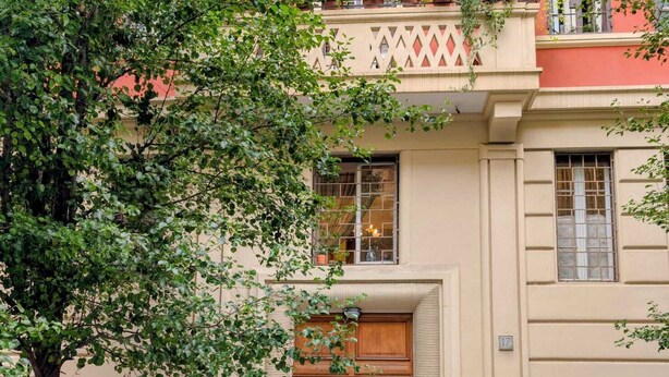 A building with a beige facade, a wooden door, and a balcony with potted plants. - Family-friendly apartment. 20 min walk to Vatican and shoping areas. (Roma)