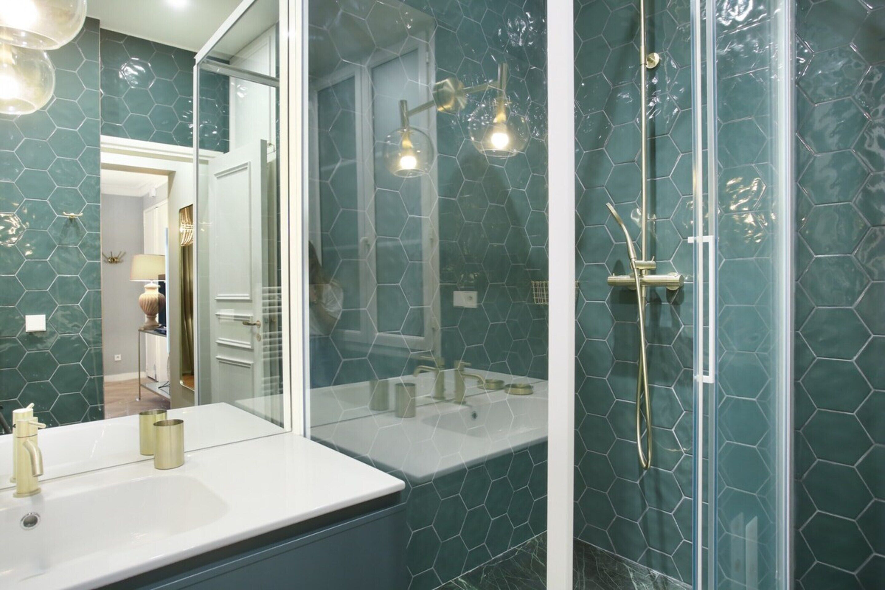 A bathroom with a glass-enclosed shower, a white sink, and a large mirror.
