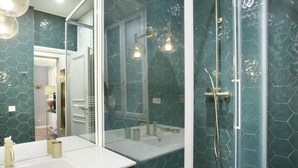 Un bagno con doccia vetrata, lavandino bianco e uno specchio grande.