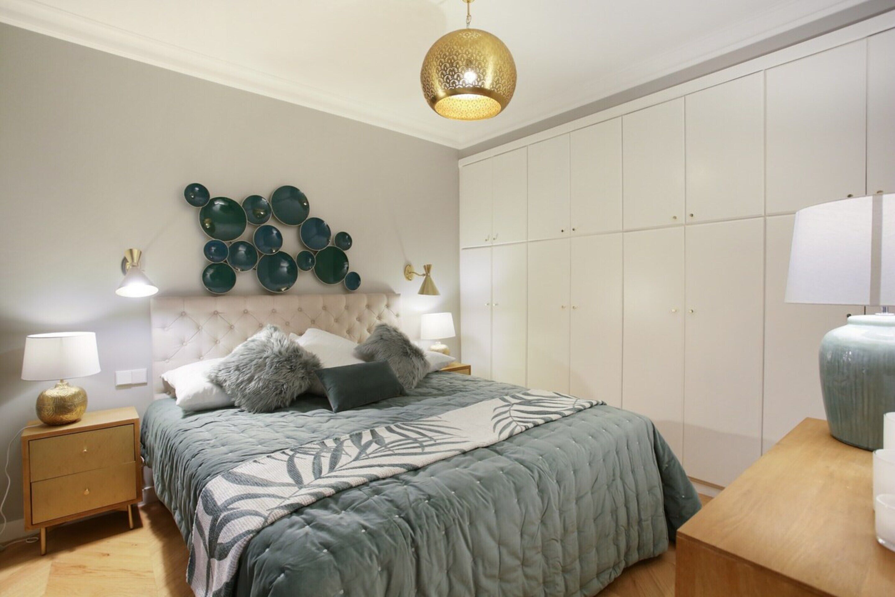 Ein Schlafzimmer mit einem Bett, Nachttischen, einer Wandleuchte und einem Kleiderschrank.