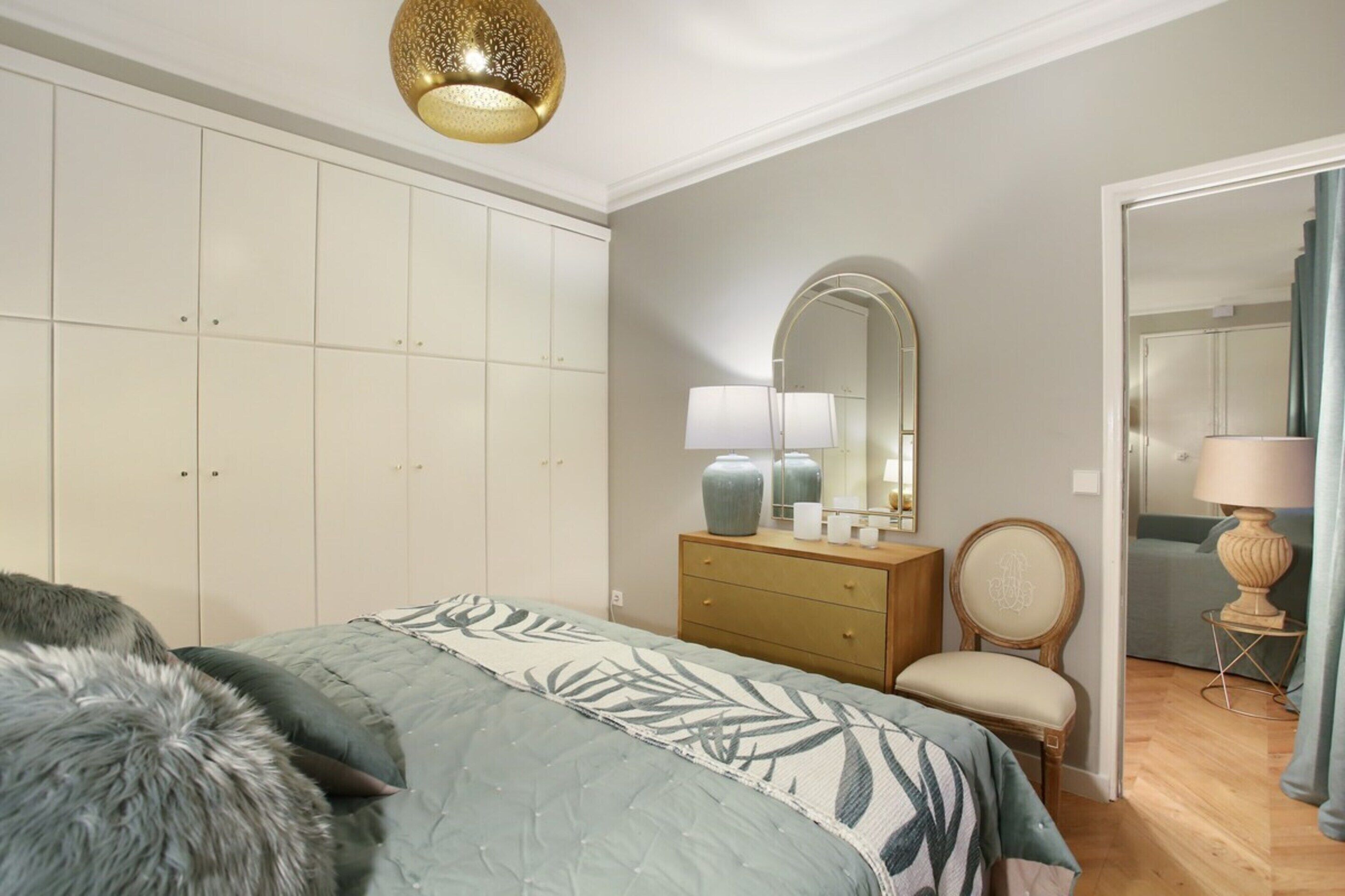 Une chambre à coucher comprenant un lit, une armoire, une commode, une chaise et un miroir.