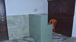 Una habitación con piso de mármol, pared de acento verde, puerta de madera y reja marrón oscuro.