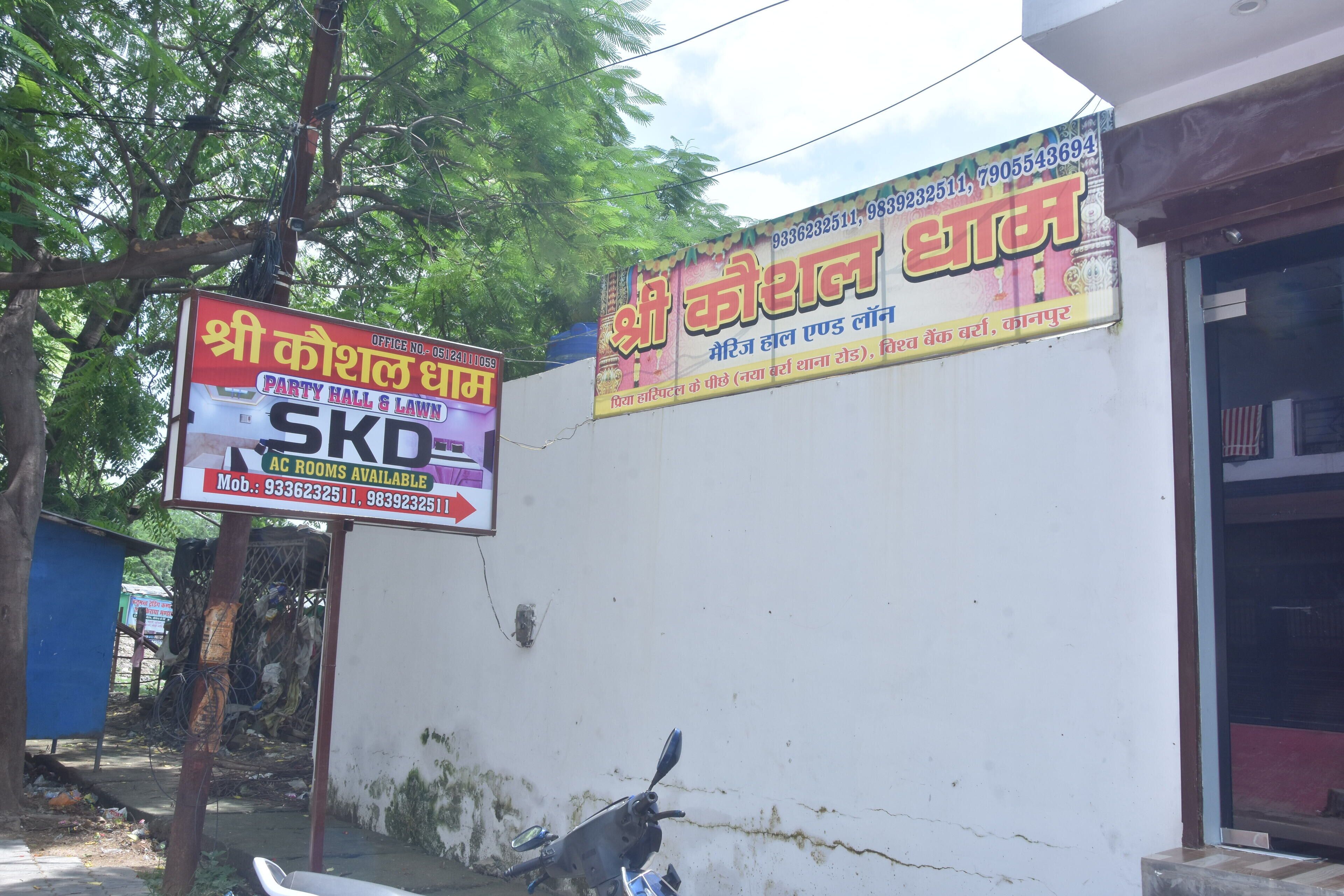 A wall with two signs advertising services. One sign is for a party hall and lawn, and the other is for a wedding hall.