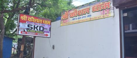 A wall with two signs advertising services. One sign is for a party hall and lawn, and the other is for a wedding hall.