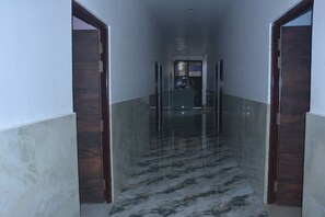 A hallway with marble flooring, wooden doors, and a glass partition. - SKD  (Kanpur)