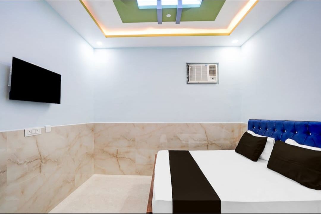 Una habitación de hotel con una cama, un televisor de pantalla plana, un aire acondicionado e iluminación empotrada en el techo.
