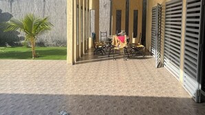 An outdoor patio area with a tiled floor, a small palm tree, and a table with chairs. - Luxury villa with private pool and staff close to the beach and Saly (N'Guerigne Bambara)