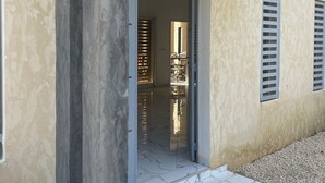 A modern building with a concrete pillar, a tiled entrance, and a visible interior with a dining area. - Luxury villa with private pool and staff close to the beach and Saly (N'Guerigne Bambara)