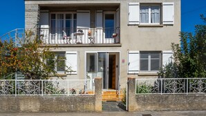 A two-story building with a balcony, a staircase, and a gated entrance. - Waterfront Apartment with Garden (Limoux)