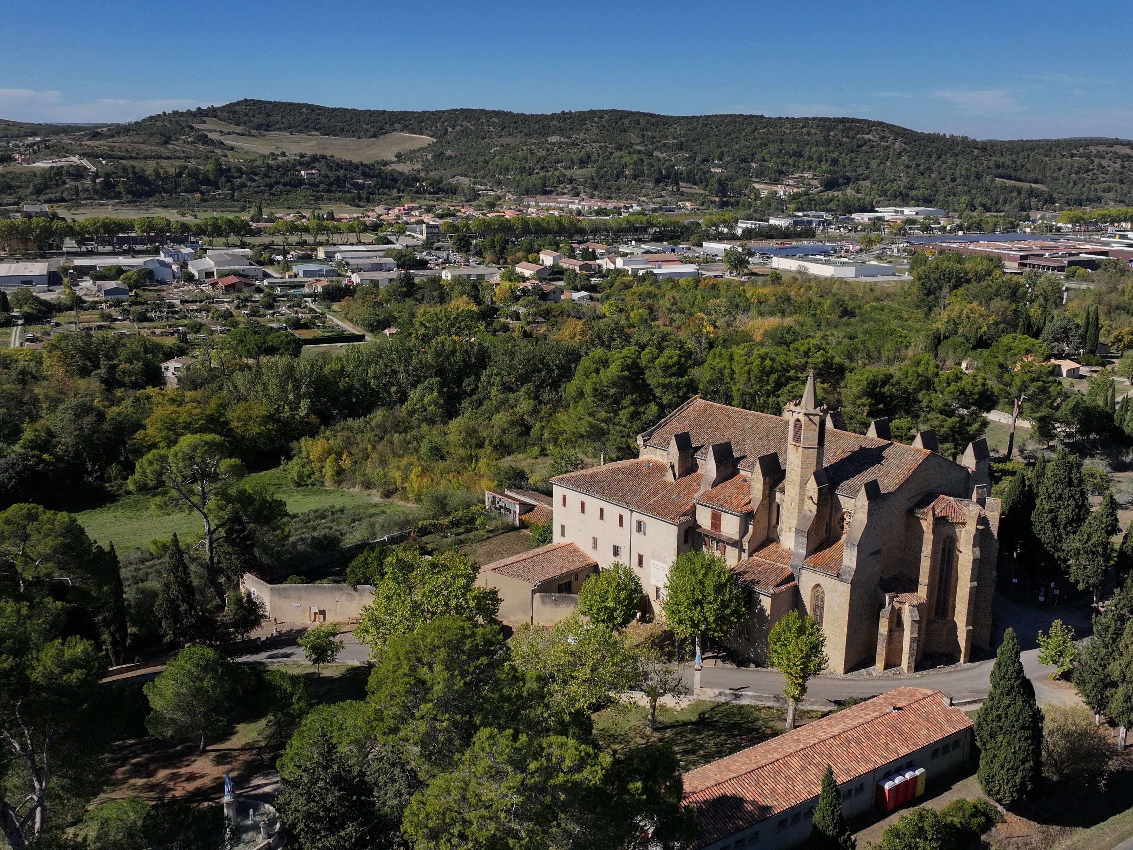 A historic building with a bell tower, surrounded by trees and a small village.