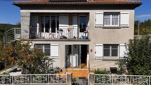 A two-story building with a balcony, a staircase, and a gated entrance. - Waterfront Apartment with Garden (Limoux)