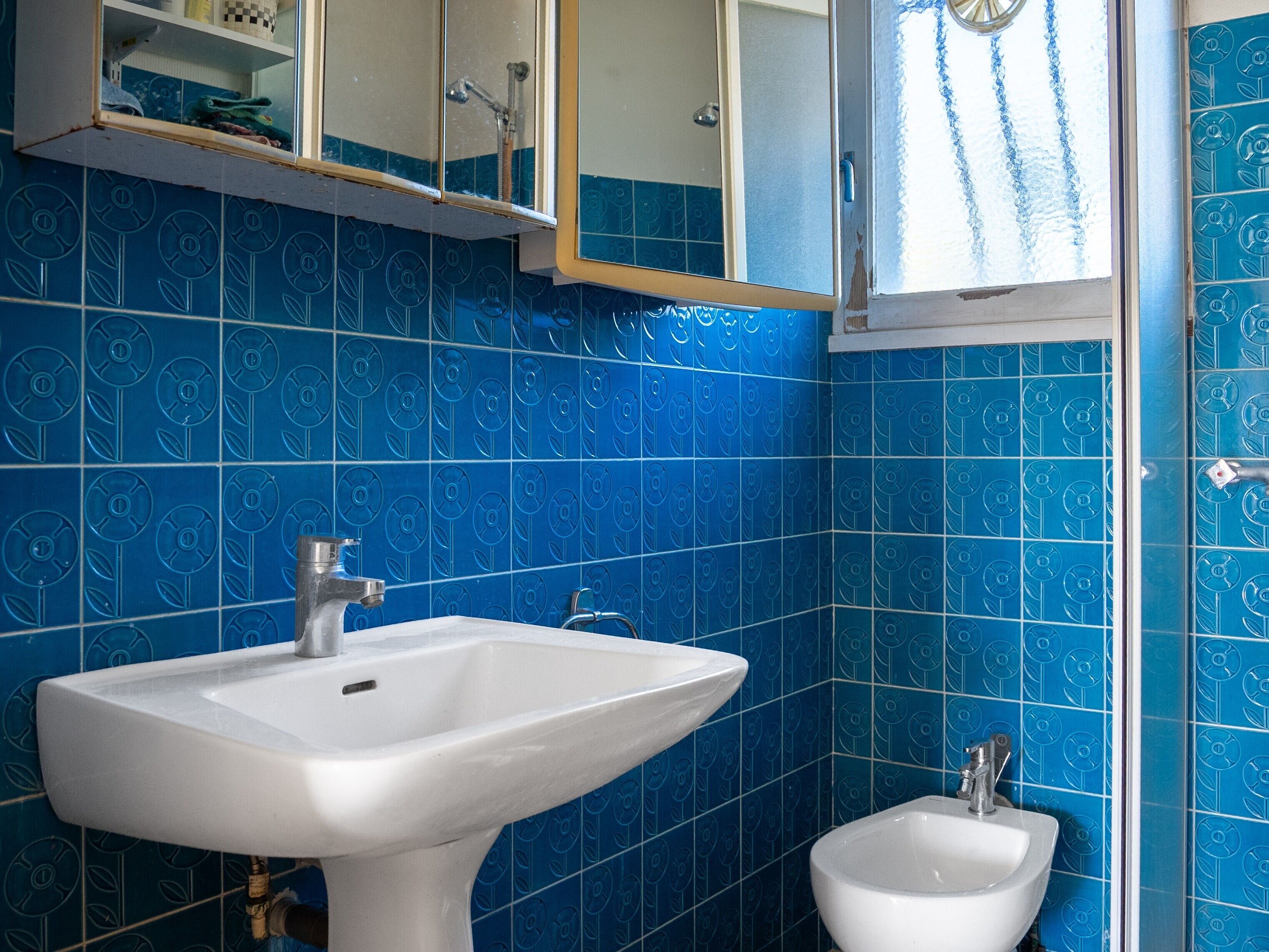 Une salle de bain avec un lavabo blanc, un bidet et un miroir au-dessus du lavabo.