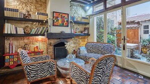 A cozy living room with a fireplace, bookshelves, and zebra-patterned furniture. - Superbe Apartment Le Marais/place des Vosges (Paris)
