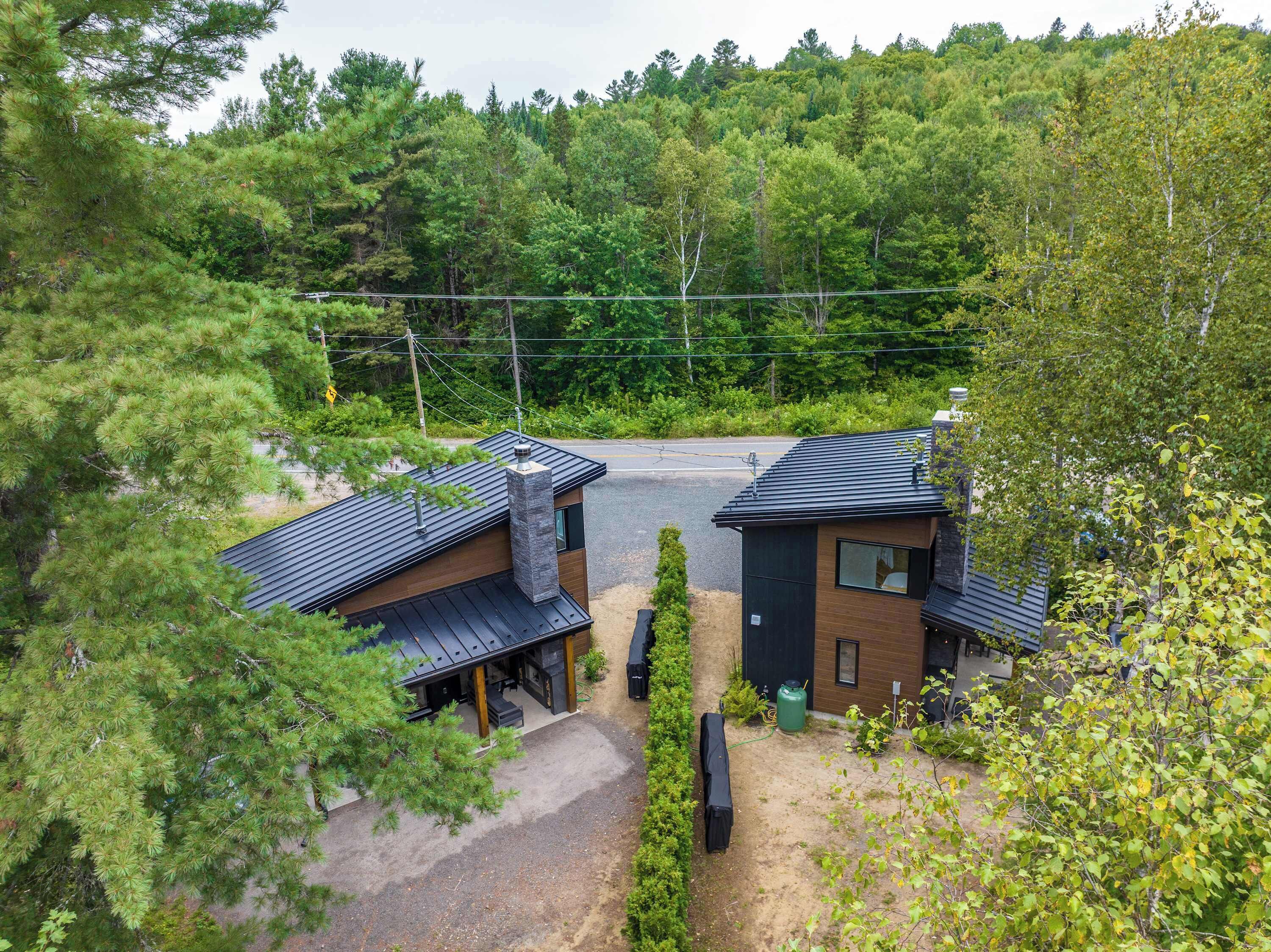 A modern two-story building with a covered outdoor area, surrounded by dense forest.