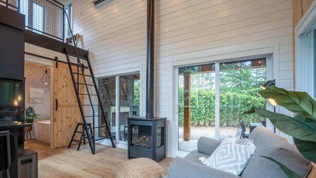 Een moderne woonkamer met een open haard, een bank, een ladder en een groot raam.