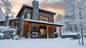 Ein modernes, zweistöckiges Haus mit Kamin, Außenbereich und verschneiter Landschaft.
