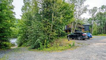 A gravel driveway leading to a cabin surrounded by dense forest.