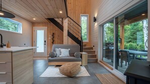 Ein modernes Interieur mit Holzboden, einer Treppe, einem Sofa und einem Essbereich mit Glastüren.
