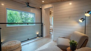 Ein modernes Interieur mit einem großen Fenster, Holzboden und einer Sitzecke mit einer Pflanze.