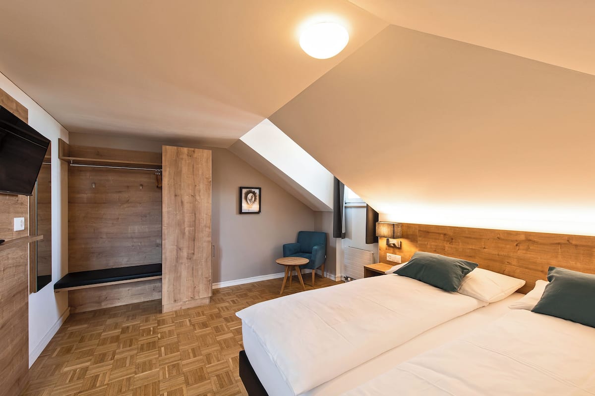 Une chambre avec un grand lit, un petit bureau, une chaise et un banc en bois.