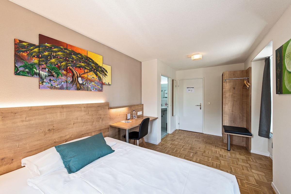 Une chambre d’hôtel équipée d’un lit, d’un bureau et d’un espace douche.