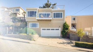 A two-story residential building with a balcony on the upper floor, a garage, and a well-maintained front yard. - @ Marbella Lane - Ocean Views & Heavenly Sunset (Pacifica)