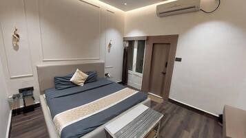 Un dormitorio moderno con cama, mesita de noche y unidad de aire acondicionado.