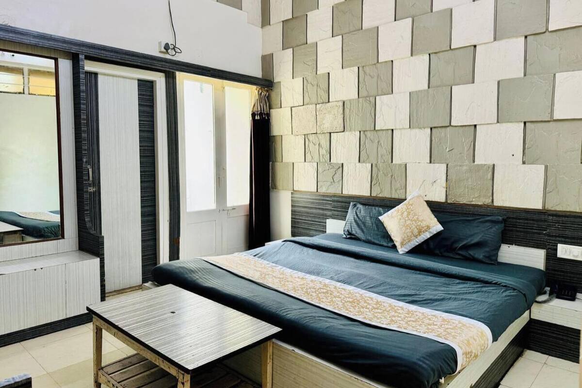 Ein modernes Schlafzimmer mit Bett, Nachttisch und Blick ins Freie durch ein Fenster.