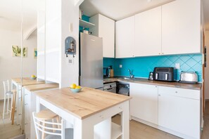Una cocina moderna con armarios blancos, una mesa de madera y un salpicadero azul.