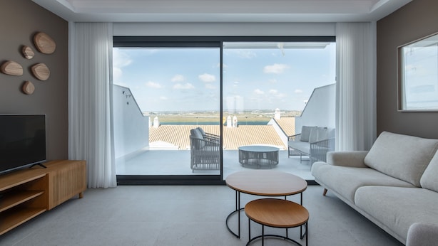 Una sala de estar moderna con un amplio ventanal corredera que da a una terraza en la azotea.