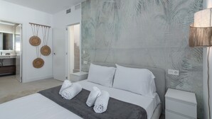 Una habitación de hotel moderna con cama, mesitas de noche, un espejo y una pared con diseño de hojas.