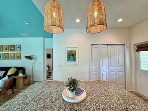A spacious living room with a large rug, a coffee table with a plant, and a bookshelf. There are two doors and a window with blinds. - The Royal Cypress Suite, Near UF, Shands, Downtown (Gainesville)