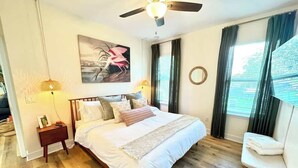 A bedroom with a bed, bedside table, lamp, and a painting on the wall. - The Royal Cypress Suite, Near UF, Shands, Downtown (Gainesville)