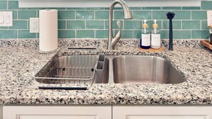 A kitchen with a double sink, granite countertop, and a window with a view of trees. - The Royal Cypress Suite, Near UF, Shands, Downtown (Gainesville)