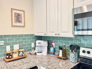 A kitchen with white cabinets, a coffee maker, a bottle of coffee creamer, and a spice rack. - The Royal Cypress Suite, Near UF, Shands, Downtown (Gainesville)