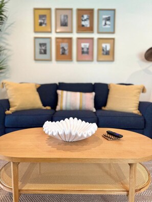 A round coffee table with a white, scalloped edge bowl in the center, a remote control, and a chessboard on the table.