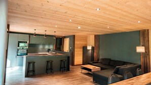 A modern kitchen with a central island, bar stools, and a dining table.