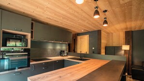 A modern kitchen with a wooden ceiling, built-in appliances, and a large island.