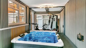 A spa room with a hot tub, exercise equipment, and a view of the city.