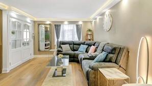 A modern living room with a sectional sofa, a glass coffee table, and a white door with frosted glass panels.