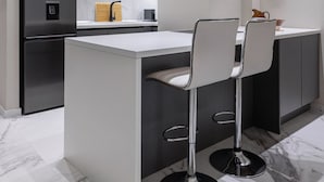 Een moderne keuken met een centraal eiland, roestvrijstalen apparatuur en een marmeren vloer.