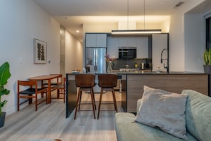A modern kitchen with a central island, bar stools, and a dining table with chairs.