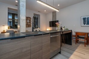 A modern kitchen with a large island, built-in appliances, and a dining area with a wooden table and chairs.