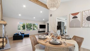 Un comedor moderno con una mesa redonda dispuesta para cuatro personas, rodeada de sillas de mimbre.