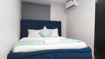 A bed with a blue upholstered headboard, white bedding, and a light blue throw blanket.