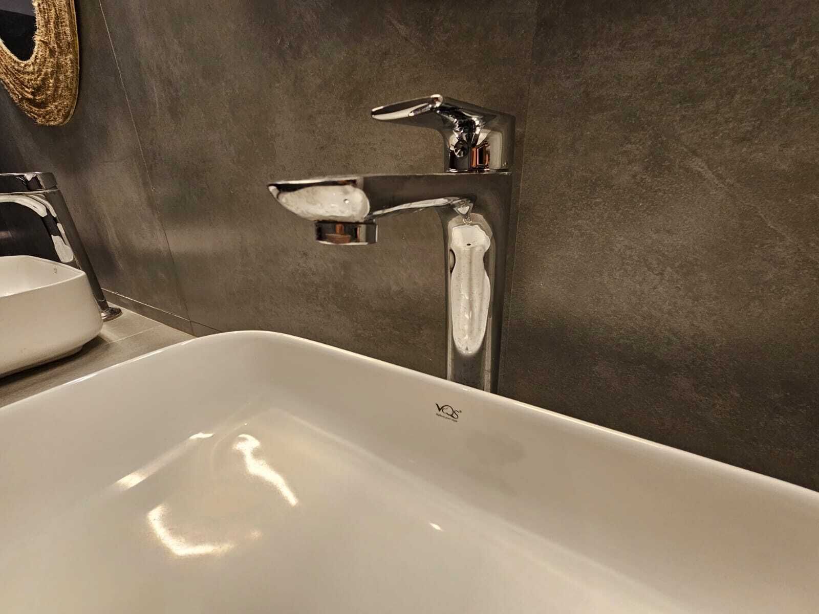 A modern bathroom with a white sink and a chrome faucet.