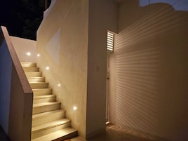 Uma escadaria com design moderno que leva a uma porta com parede texturizada.